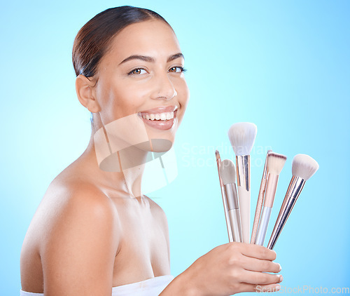 Image of Cosmetic, makeup brushes and portrait of a woman in a studio for a beauty, natural and face routine. Cosmetics, skincare and female model from Brazil with a facial glow isolated by a blue background.