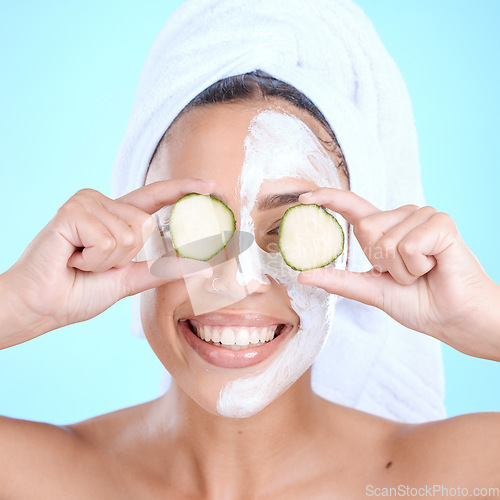 Image of Beauty, cucumber and skincare face mask on a woman with vegetable slice for dermatology cosmetics. Aesthetic model person with spa facial for self care, skin glow and wellness on blue background