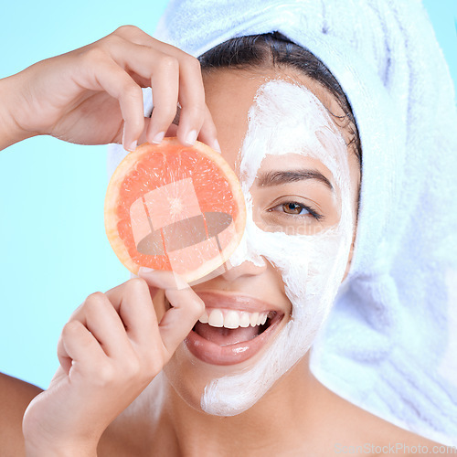 Image of Portrait, skincare and woman with grapefruit mask in studio for beauty, hair and cosmetics on blue background, Face, facial and girl model relax with fruit, luxury and product, wellness or isolated