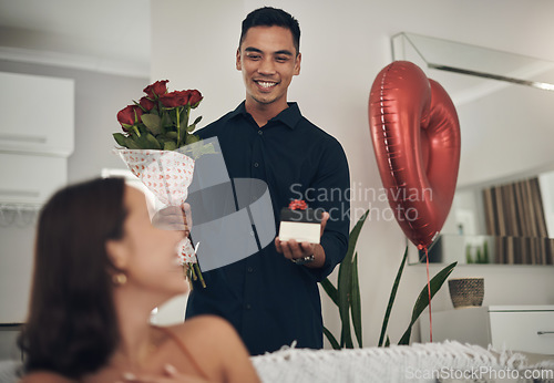 Image of Surprise, love and man with a gift and roses for his wife for valentines day, romance or anniversary. Happy, romantic and husband with present and bouquet of flowers for his woman in the living room.