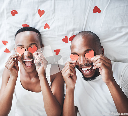 Image of Heart, bedroom and overhead with a valentines day black couple lying on a bed in their home together. Love, face or emoji with a romantic man and woman dating in their house to relax from above