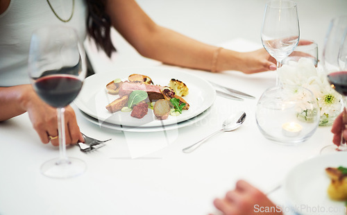 Image of Couple, table and food at restaurant in closeup for valentines day date, bonding or romance in night. Man, woman and red wine glass with fine dining, service and hands for dinner, love or celebration