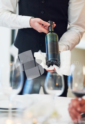 Image of Waiter hands, wine and restaurant table with white towel, luxury hospitality and vintage for fine dining. Man, bottle service and holding drink for customer decision at celebration on valentines day