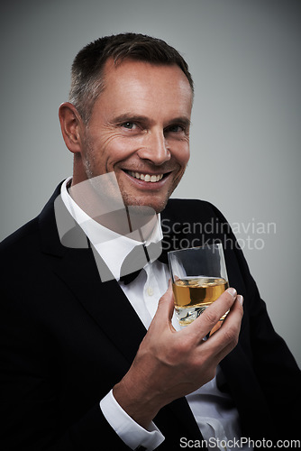 Image of Tuxedo, whiskey glass and man portrait with alcohol in a suit feeling classy with a luxury drink. Gray background, isolated and studio with a model, agent or actor smile with rich drinking