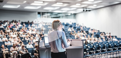 Image of Female speaker giving a talk on corporate business conference. Unrecognizable people in audience at conference hall. Business and Entrepreneurship event.