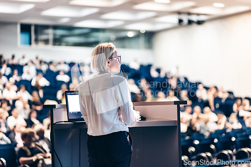 Image of Female speaker giving a talk on corporate business conference. Unrecognizable people in audience at conference hall. Business and Entrepreneurship event.