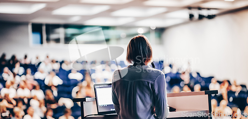 Image of Female speaker giving a talk on corporate business conference. Unrecognizable people in audience at conference hall. Business and Entrepreneurship event.