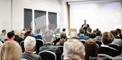 Image of Speaker giving a talk in conference hall at business event. Rear view of unrecognizable people in audience at the conference hall. Business and entrepreneurship concept.