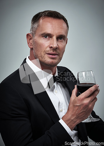 Image of Tuxedo, red wine and spy man with alcohol in a suit feeling classy with a luxury drink. Gray background, isolated and studio with a model, agent or actor with a glass and rich person with mockup