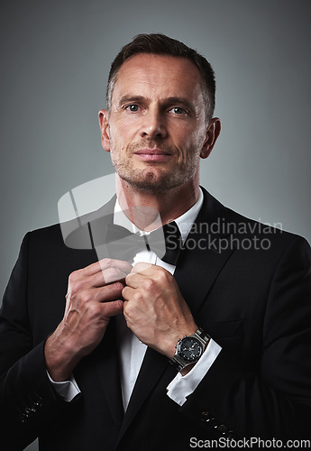 Image of Studio portrait of gentleman in tuxedo, fixing tie and serious, isolated on grey background. Luxury, fashion and and man with wealth, success and celebrity actor style, date for valentines day.