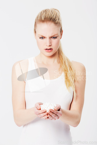 Image of Confused, shocked and woman holding pills in her hands or overdose isolated against a studio white background. Medicine, capsules and annoyed female with tablets due to mental health issues