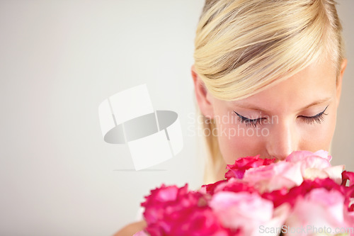 Image of Smelling, floral and woman with flowers as a gift isolated on a grey studio background. Surprise, romantic and girl with a bouquet of roses for valentines day on a backdrop with mockup space