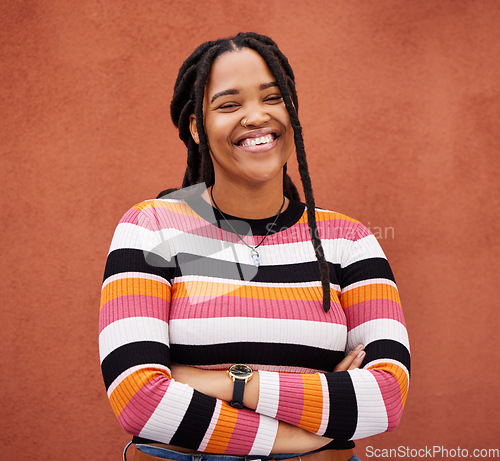 Image of Happy, smile and portrait of a black woman by a wall in city while walking for adventure. Happiness, freedom and African female posing with crossed arms in a town on holiday, vacation or weekend trip