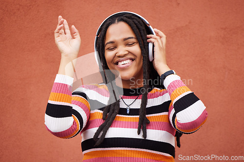 Image of Black woman, music headphones and wall with smile in city for walk, adventure and listening to edm on radio. Young gen z girl, streaming hip hop or techno on website, internet and happiness in metro