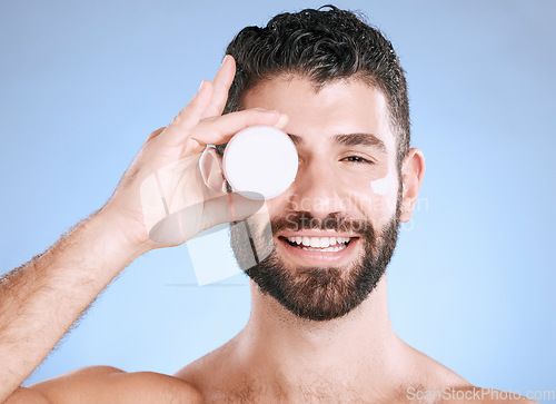 Image of Cream, skincare jar and man for face, body and happy cosmetics in studio blue background. Facial lotion, male portrait and product for beauty, container and aesthetic for healthy glow, shine or smile