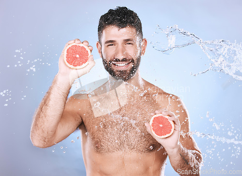 Image of Grapefruit, water splash and man on blue background for wellness benefits, beauty and skincare. Male model, portrait and citrus fruits for vitamin c cosmetics, detox and nutrition for healthy shower