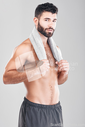 Image of Health, fitness and body portrait of man with towel on neck, sports workout and hygiene isolated on grey background. Sweat, confidence and male model smile, self care mindset for exercise in studio.