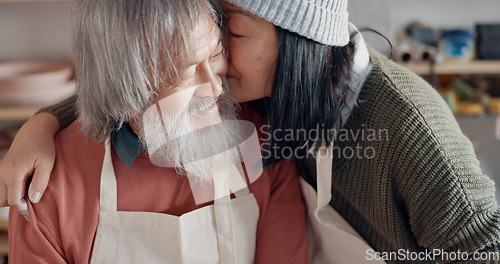 Image of Pottery, creative and senior couple talking about art with hug and kiss together in a studio class. Elderly Asian man and woman hugging with love while learning and working with clay on a date