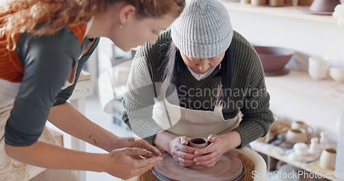 Image of Pottery teacher, studio and workshop learning, training and teaching to seniorwoman on craft wheel for creativity, clay and sculpture process. Artist helping student in class, design and creative mol