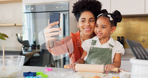 Image of Mother, girl and phone selfie while cooking in kitchen, bonding and having fun. Learning, baking and mom, kid and 5g mobile for social media, picture or online post with victory hands or peace sign
