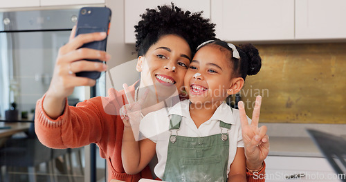 Image of Mother, girl and phone selfie while cooking in kitchen, bonding and having fun. Learning, baking and mom, kid and 5g mobile for social media, picture or online post with victory hands or peace sign