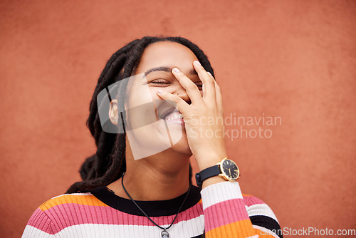 Image of Happy, laughter and freedom with a black woman on an orange background outdoor for joy or humor. Funny, laugh and smile with an african american person laughing or joking against a color wall