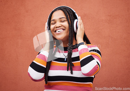 Image of Wall, black woman and headphones for happiness, radio and freedom with girl chilling, calm and relax on studio backdrop. Jamaican, happy female and lady with headset for music, streaming and podcast