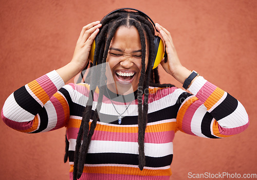 Image of Black woman, music headphones and happiness by wall in city for walk, adventure and comedy album. Young gen z girl, audio streaming and listen to comic podcast on website, radio and happy in metro