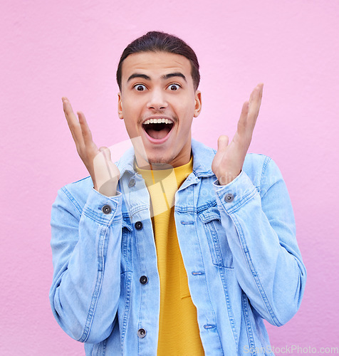 Image of Man, hands and face for surprise in portrait with happiness, excited and pink wall background. Happy gen z model, wow and smile for announcement, fashion and news for career, success and life goal