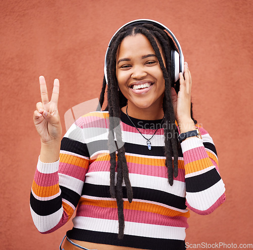 Image of Portrait, headphones and black woman with peace sign isolated on orange wall for gen z music or mental health. Young person or v hands of youth listening to audio 5g technology or streaming services