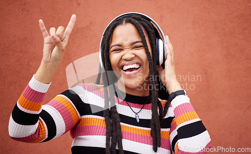 Image of Rock sign, headphones and black woman isolated on orange wall for gen z music subscription or mental health. Young person or excited youth listening to audio 5g technology or streaming services