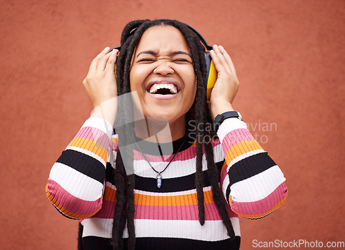 Image of Black woman, music headphones and smile by wall in city for walk, adventure or happy laughing for comedy. Young gen z girl, audio streaming or comic podcast on website, internet or happiness in metro