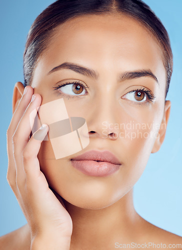 Image of Skincare, beauty and woman in a studio with a natural, organic and cosmetic facial treatment. Self care, cosmetics and female model from Brazil with a fresh skin or face routine by a blue background.