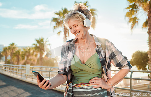 Image of Happy, music and phone with old woman at beach for streaming, freedom and summer break. Internet, technology and headphones with senior lady listening to online radio for podcast, audio and media