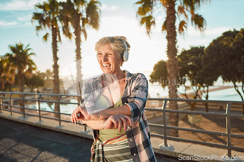 Image of Happy old woman, headphones and music on holiday at tropical island resort with smile and palm trees. Summer, happiness and funky grandma streaming 5g radio service on retirement vacation in Hawaii.