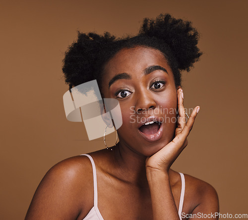 Image of Beauty, skincare and portrait of shocked black woman with hand in face isolated on brown background. Surprise, wow and facial cosmetics or natural makeup for healthy, glowing skin on model in studio.