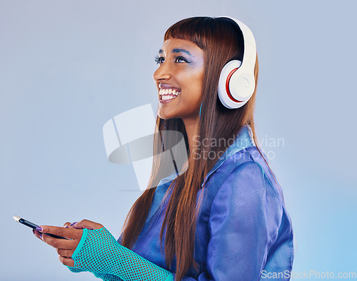 Image of Headphones, black woman and phone isolated on blue background for cyberpunk fashion and gen z thinking. Young person or beauty model with idea or listening to music on smartphone technology in studio