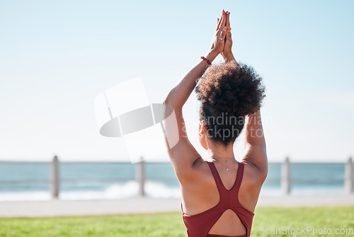 Image of Fitness, black woman and yoga meditation by beach for spiritual wellness or exercise in nature. Sporty female yogi back in warm up arm stretch for zen workout, relax or meditating by ocean coast