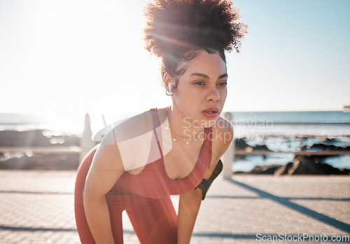 Image of Exercise, music and tired with a black woman runner on the promenade for cardio or endurance training. Fitness, running and earphones with a sports person feeling exhausted during her workout