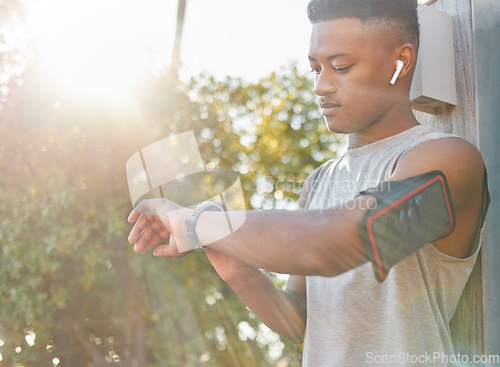 Image of Fitness, black man and watch checking time or performance for running exercise, workout or training in nature. African American male runner looking at wristwatch for tracking or monitoring cardio