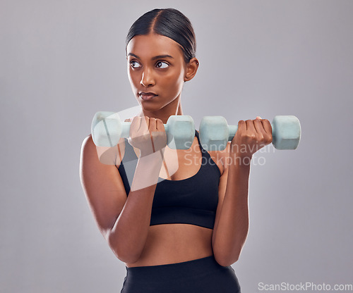 Image of Woman, focus and dumbbell training in studio for strong body, action or thinking of mindset goals. Indian female, bodybuilder and weights of fitness, power exercise or muscle energy of sports workout