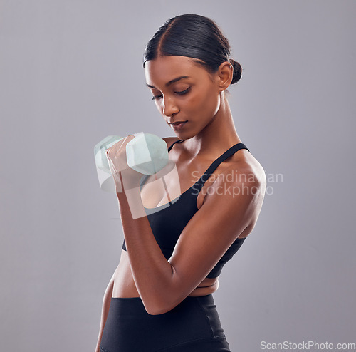 Image of Black woman, dumbbells training and studio for muscle development, wellness and self care with focus. Gen z bodybuilder girl, exercise and strong healthy body with gym equipment by gray background