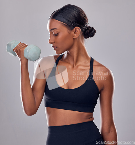 Image of Black woman, dumbbells exercise and studio for muscle development, wellness and self care with focus. Gen z bodybuilder girl, training and strong healthy body with gym equipment by gray background