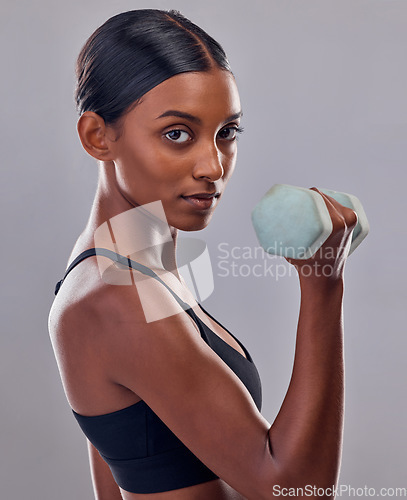 Image of Woman, portrait and bicep with dumbbell in studio for strong body, action and focus exercise. Indian female, bodybuilder and weights of fitness, power training and muscle energy for sports workout