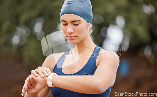 Image of Woman swimmer, looking and smartwatch for training, time or wellness for development, exercise or contest. Girl, swimming workout and check watch for health, heart rate or focus by blurred background