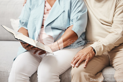 Image of Hands, bible and praying with an old couple reading a book together in the home during retirement. Jesus, faith or belief with a senior man and woman in prayer to god in a house for spiritual bonding