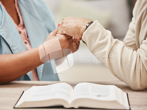 Image of Hands, bible and pray with a senior couple reading a book together in their home during retirement. Jesus, faith or belief with a man and woman praying to god in their house for spiritual bonding