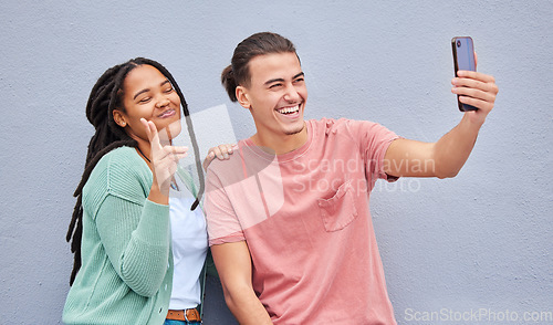 Image of Young happy couple, selfie and smile by wall with phone, profile picture and happiness in city. Influencer, man and black woman with smartphone, social media and peace sign by background in metro