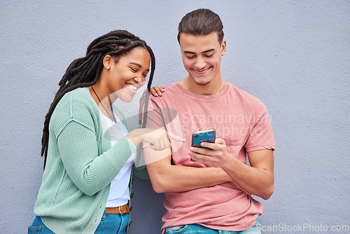 Image of Man, woman and phone by wall for meme, social media or blog post with happiness together in city. Interracial couple, smartphone and happy with smile, comic and funny video on internet app in metro