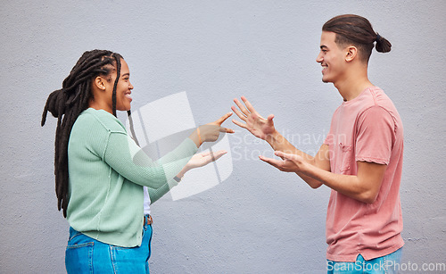 Image of Couple playing rock, paper, scissors by a wall in the city for game, decision or choice while on holiday. Playful, happy and interracial and woman having fun together in town while on a vacation.